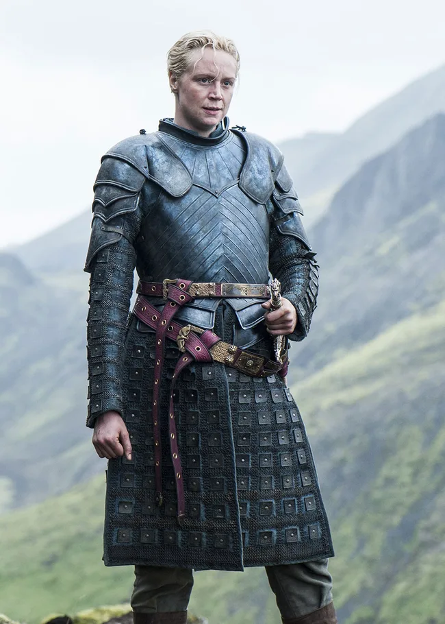 Knight in silver armor with a sword, standing in a mountainous landscape.