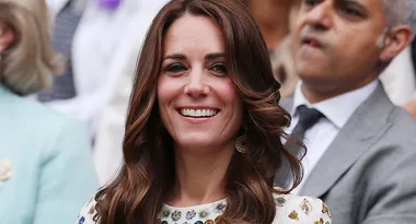 I'm sorry, I don't know who this person is. A woman smiling at an event, with people in the background.