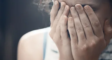 Person covering face with hands, appearing distressed or upset.