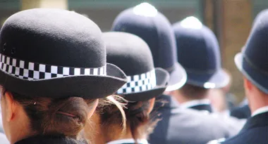 British police officers wearing helmets standing in a line, viewed from behind.
