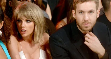 Two people sitting closely at an event, one looks surprised while the other looks thoughtful.