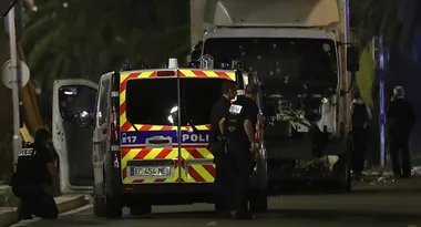 Police officers at a crime scene with damaged vehicles on a street at night.