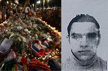 Monument of flowers and flags in Nice after an attack; blurred photo of an unidentified person on the right.