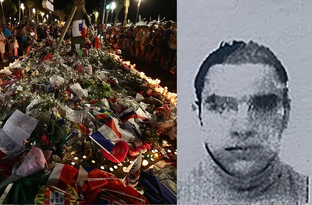 Monument of flowers and flags in Nice after an attack; blurred photo of an unidentified person on the right.