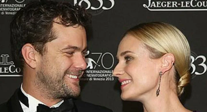 Two people smiling at each other at the 70th Venice International Film Festival, red carpet background.