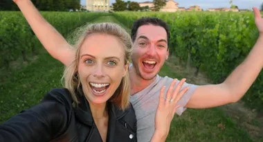 A joyful couple taking a selfie in a lush vineyard.