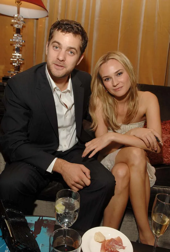 Two people sitting closely on a sofa, with drinks and appetizers on a table in front of them.