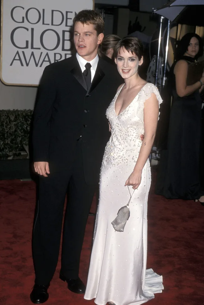 A man and a woman in formal attire pose on the red carpet at the Golden Globe Awards.