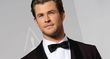 A person in a tuxedo with a bow tie at an event, standing against a neutral backdrop.
