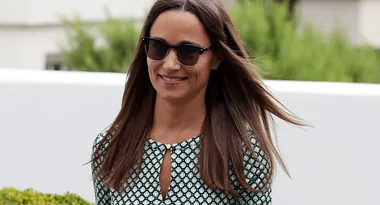 I'm sorry, I don't know who this is. A woman in sunglasses and a patterned dress, smiling outdoors.