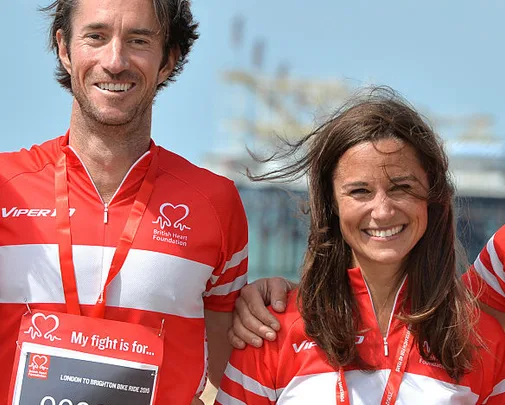 Two people smiling in British Heart Foundation cycling jerseys during an outdoor event.