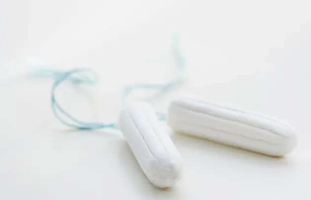 Two white tampons with blue strings on a light background.