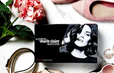 Box labeled "the Parcel by Marie Claire Ageless" with flowers, shoes, and accessories on a marble surface.