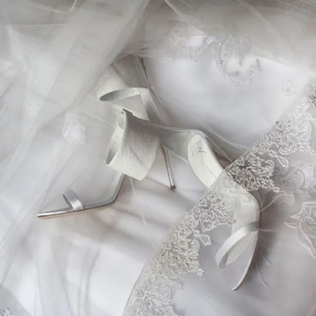White high heels with lace detail under a delicate sheer fabric.