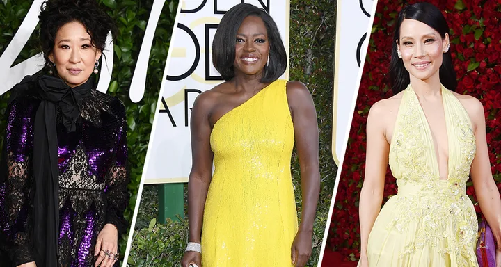 Three women posing in elegant gowns at an event; one in purple lace, middle in yellow one-shoulder, and the last in pale yellow halter.