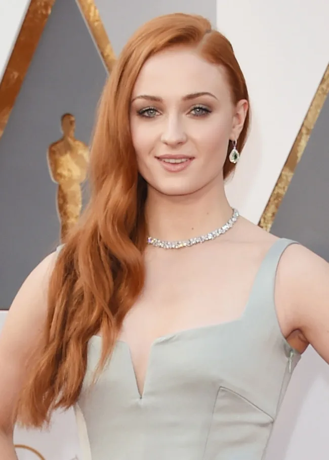 A person with long red hair in a formal dress at an event.