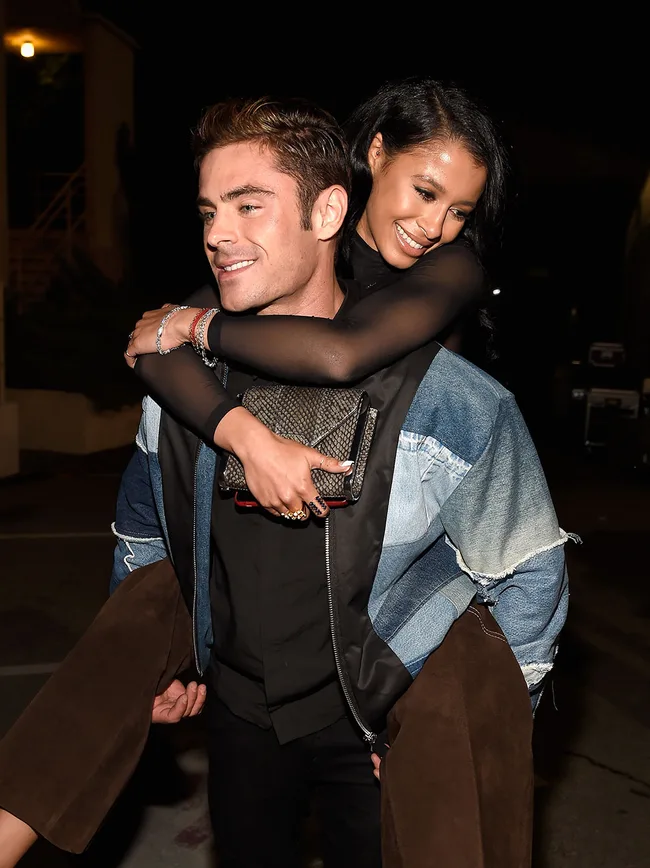 A man giving a woman a piggyback ride; both are smiling.