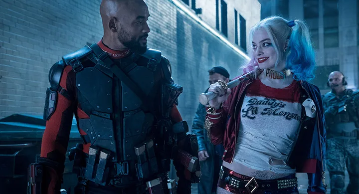 Harley Quinn and Deadshot walking in an alley at night, Harley holding a bat, both in costume from "Suicide Squad."