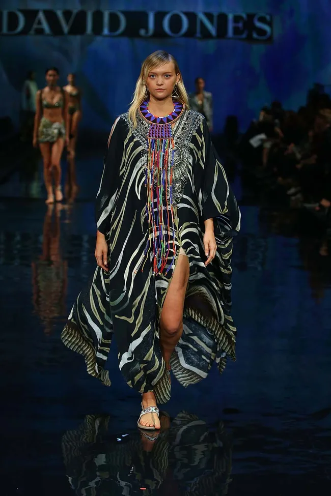 Model on runway in a flowing animal print kaftan with beaded detail, at a David Jones fashion show.
