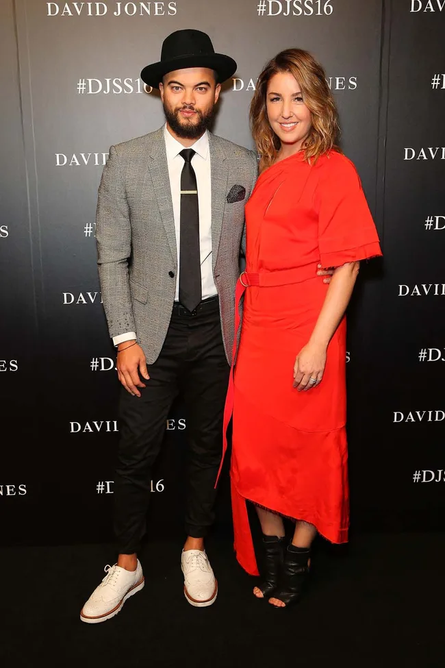 Two people posing at a David Jones event; man in hat and grey suit, woman in a red dress.