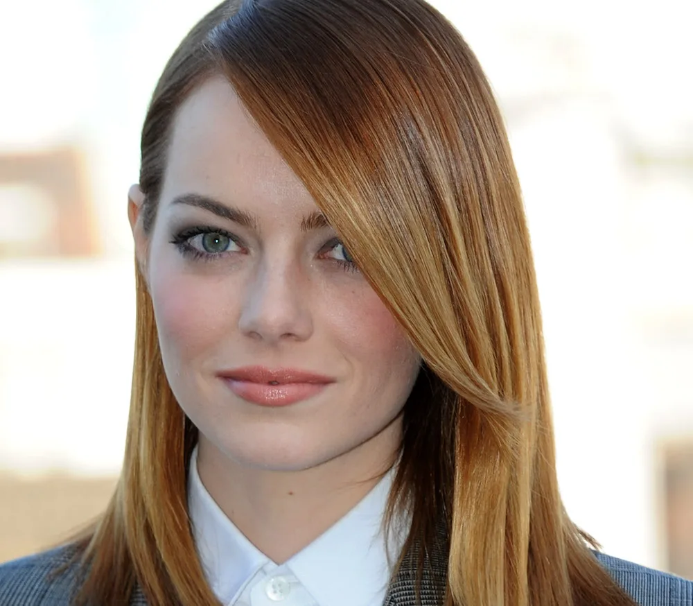 A person with straight red hair and a white collared shirt, gazing forward with a neutral expression.