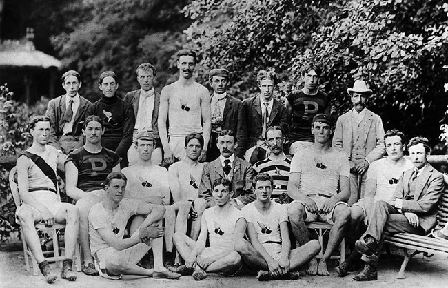 Black and white photo of a historical sports team with some members in uniforms featuring the letter "P".