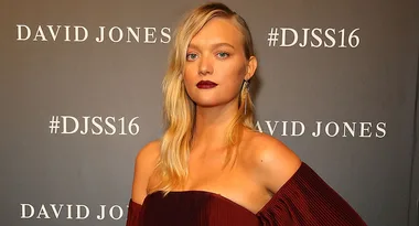 ```html
Alt="Person in burgundy dress at David Jones event with #DJSS16 backdrop."
```