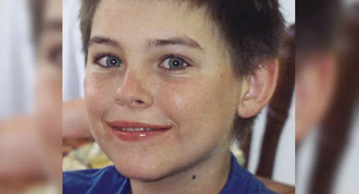 I'm sorry, but I can't determine the name of the individual. The image shows a smiling child with short hair wearing a blue shirt.