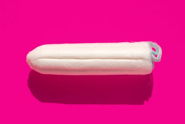 A white tampon on a vibrant pink background.