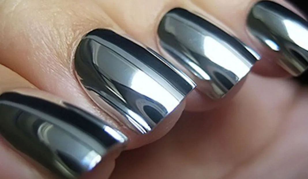 Shiny chrome finish on manicured fingernails, reflecting light.
