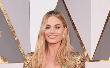 I don't know who this person is, but they're at a formal event wearing a gold dress and smiling.