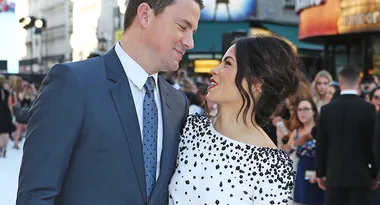 A couple dressed formally, smiling at each other on a crowded city street.
