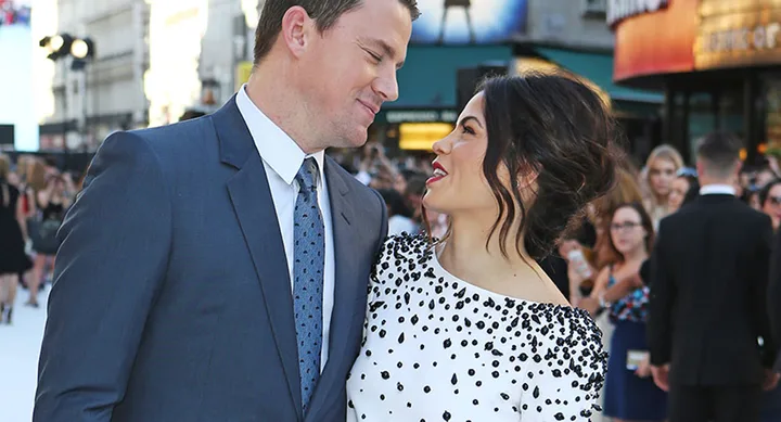 A couple dressed formally, smiling at each other on a crowded city street.
