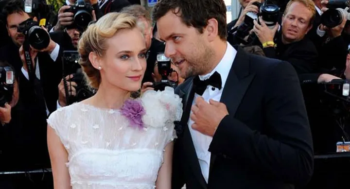 Two people in formal attire at a red carpet event, surrounded by photographers.