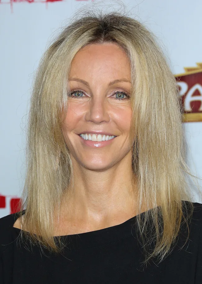 A woman with long blonde hair and a black top smiling at the camera.