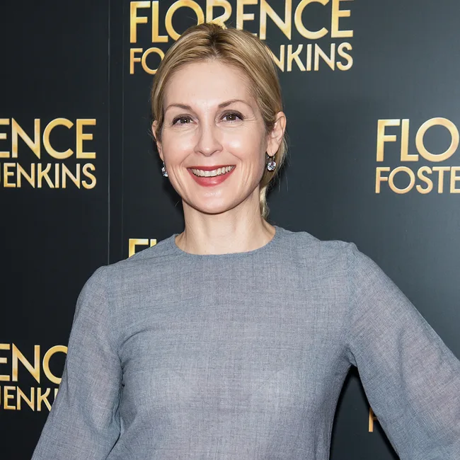 Person smiling at a "Florence Foster Jenkins" event backdrop.