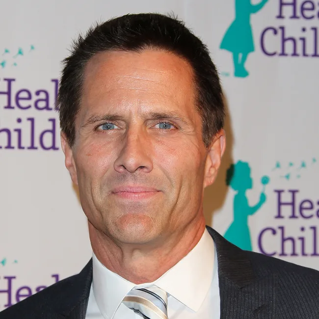 Man in a suit at a Healthy Child event with a background logo.