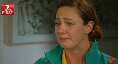 "Person wearing a green and yellow jacket appears emotional during an interview on Channel 7 News First."