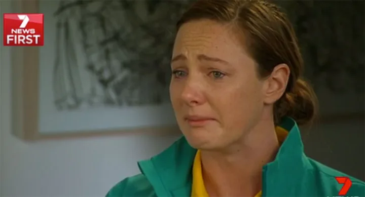 "Person wearing a green and yellow jacket appears emotional during an interview on Channel 7 News First."