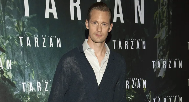 A person at "La Leyenda de Tarzan" event, standing in front of the event backdrop.