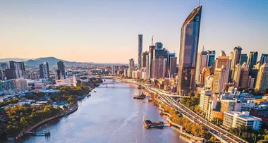 Aerial view of Brisbane city skyline with the Brisbane River in the foreground during sunset.