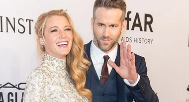 A couple smiling at a formal event, the man waves to the camera.