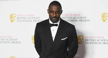 Black-tie event attendee at British Academy Television Awards, standing against branded backdrop.