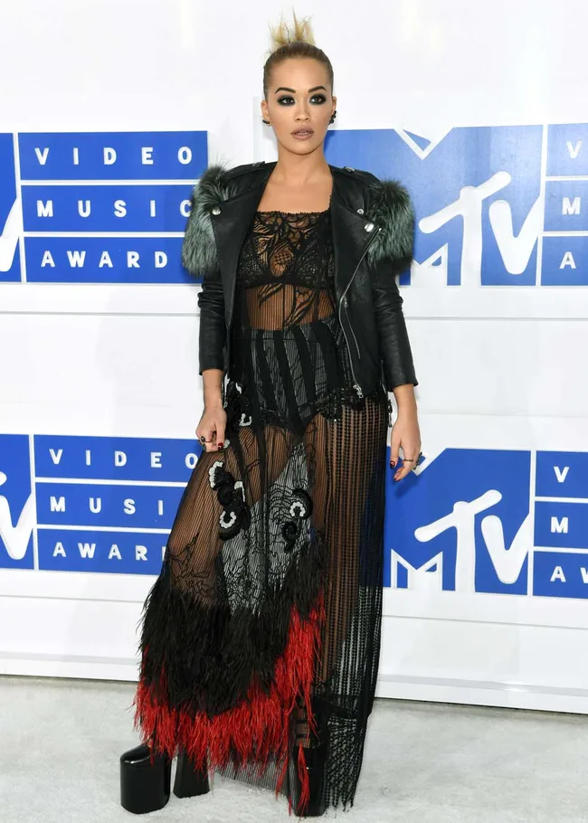 Person in sheer black and red dress with a leather jacket at MTV Video Music Awards.