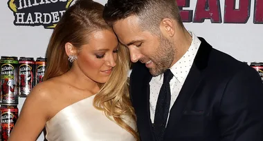 A couple poses on the red carpet, with the man in a suit and the woman in an elegant dress.