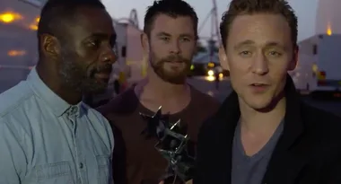 Three men standing together outdoors, one holding a star-shaped award.