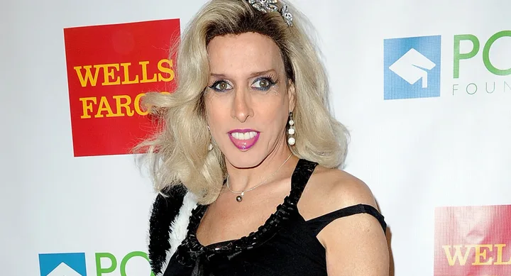 Blonde woman in a black dress with jewelry, standing in front of a Wells Fargo and PONY Foundation backdrop.