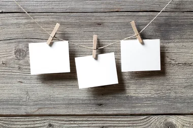 Three blank notes clipped to a string on a wooden background.