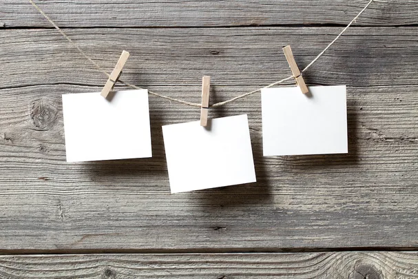 Three blank notes clipped to a string on a wooden background.