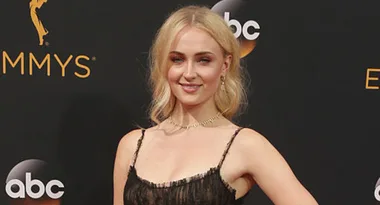 A woman in a black dress stands on the red carpet at an Emmy Awards event, smiling, with ABC logo in the background.